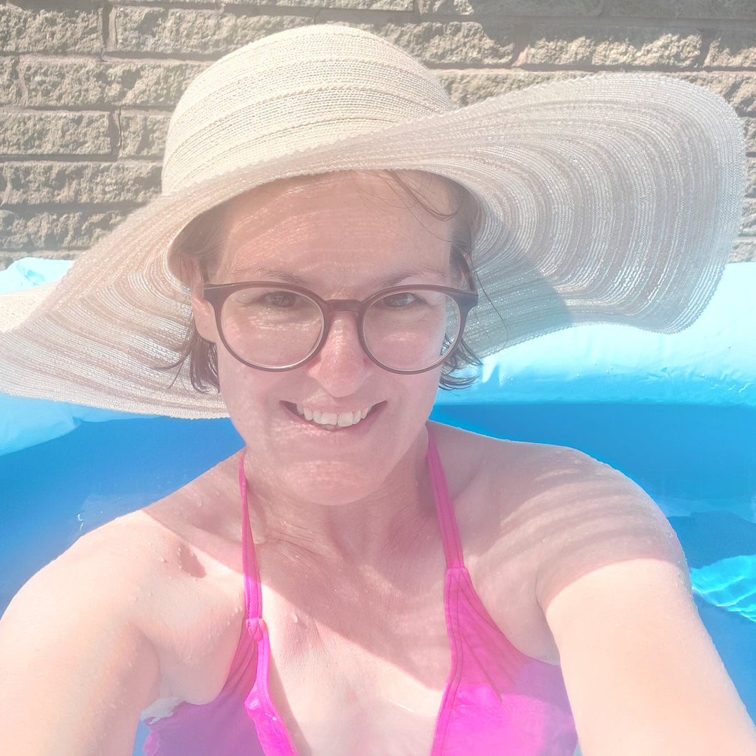 In pink bikini and straw sunhat.