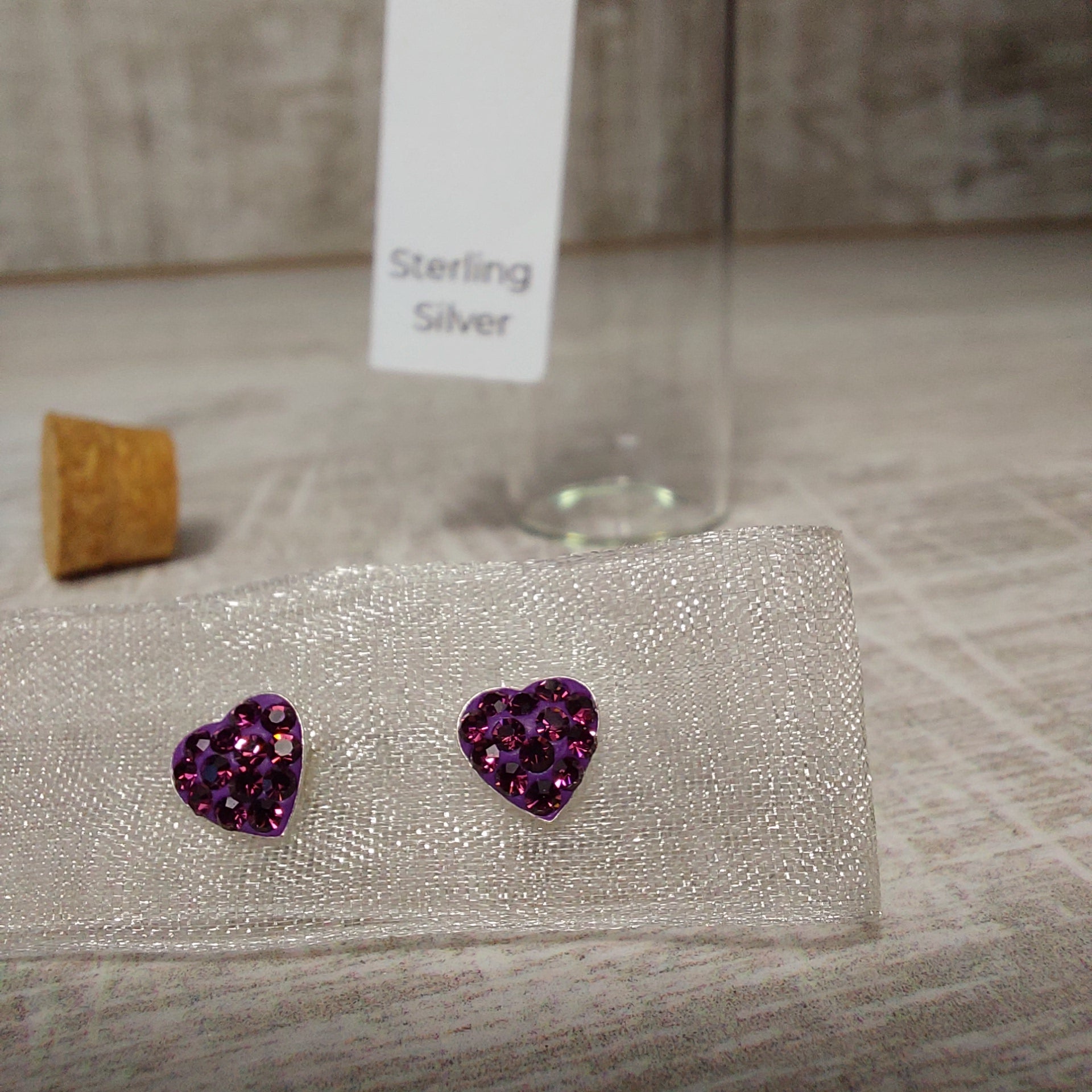 Pair of purple amethyst earrings on a fabric background with words sterling silver.