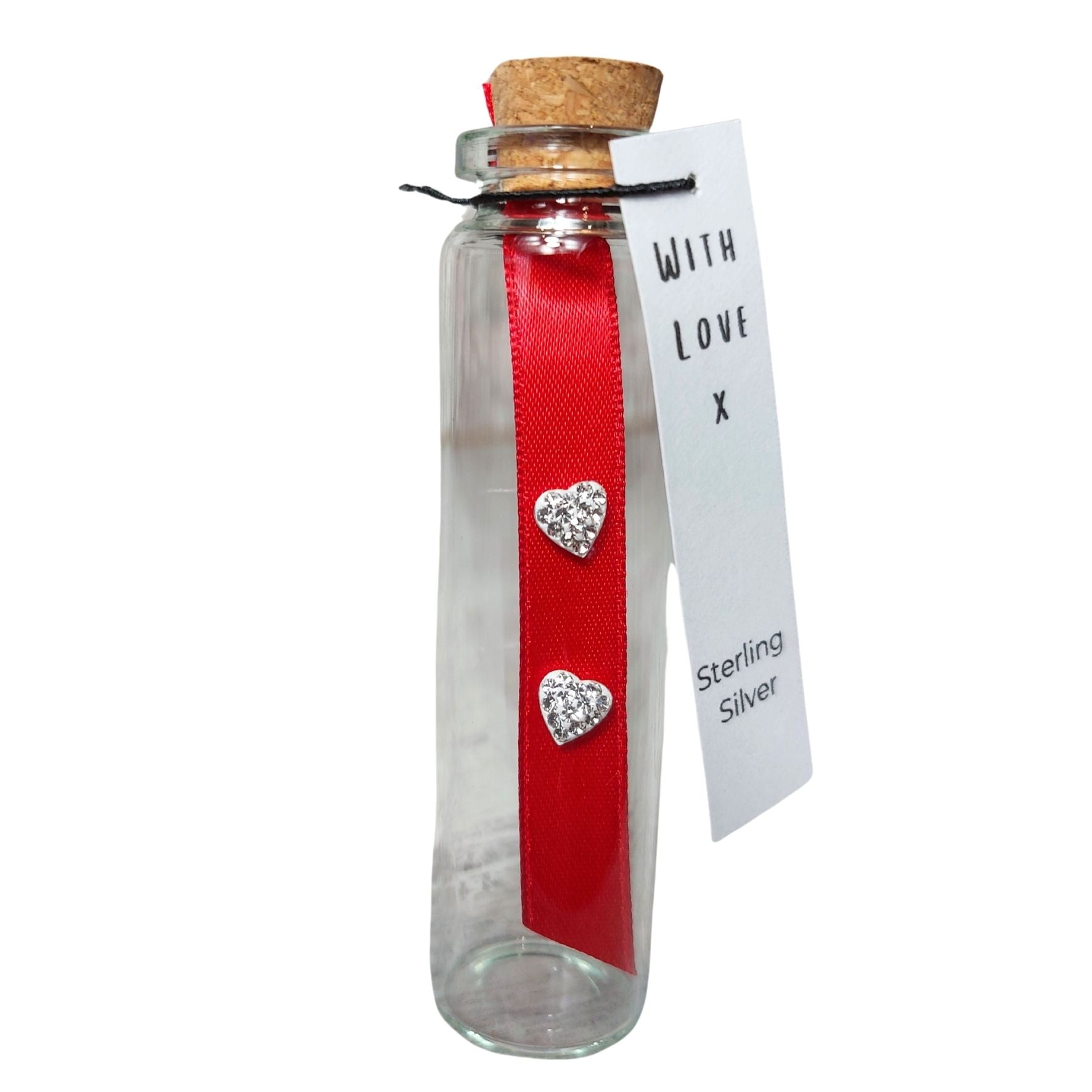 Pair of heart shaped crystal earrings on a red ribbon. These are presented in a cork topped glass bottle and have a gift tag attached. The gift tag has the words With Love and  sterling silver.