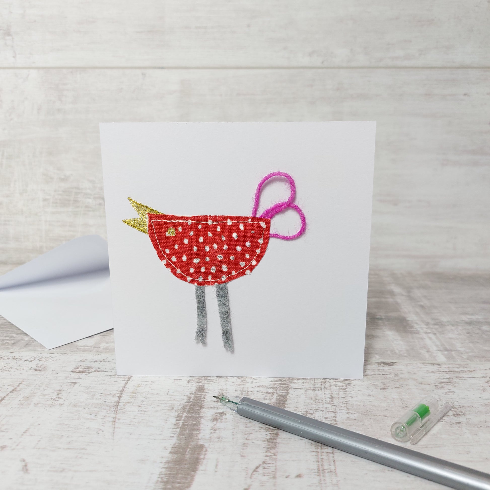 Square greetings card with fabric stitched bird. With wool tail, felt legs and gold beak detail.